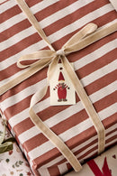 Et stemningsbillede af julegaver, som er pakket ind i rød og hvid stribet papir, med en creme farvet stofsnor bundet omkring. 