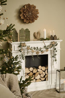 Et stemningsbillede, af en pejs med brænde i, et pyntet juletræ med gaver under ved siden af, kalenderlys og pynt på pejsen, og mere pynt rundt om. 